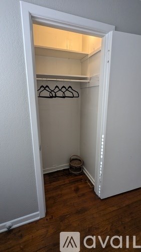 A small closet with a light on and a bowl on the floor.