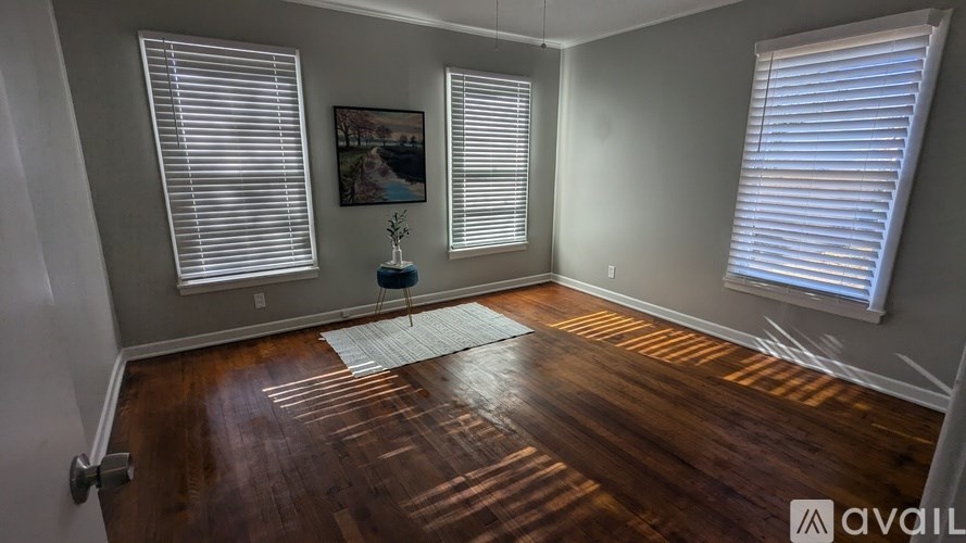A room with wooden floors and two windows with blinds.