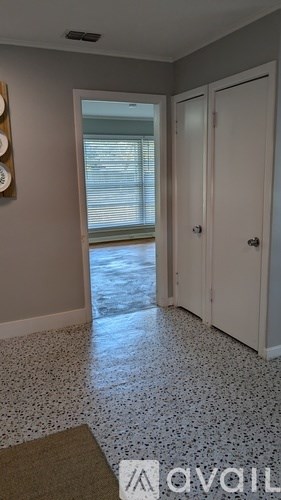 A hallway with a tiled floor and a door on the right.