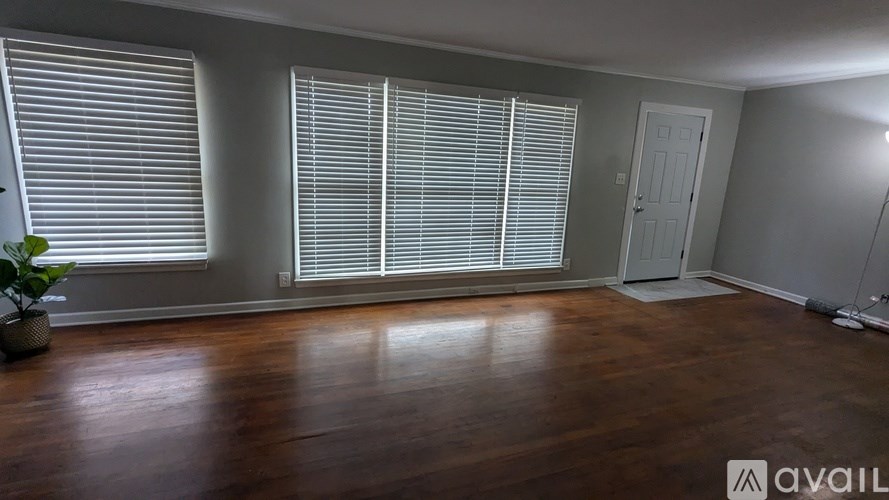 A room with wooden floors and a door is available for rent.