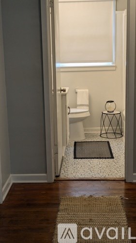 A bathroom with a towel hanging on the door and a rug on the floor.