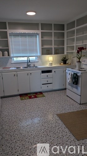 A kitchen with white cabinets and a speckled floor.