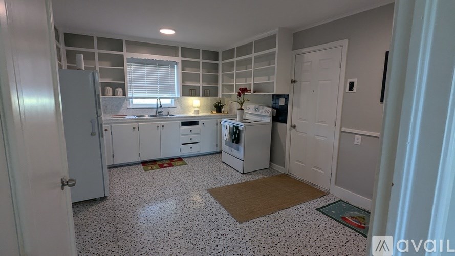 A kitchen with white cabinets and a white fridge.