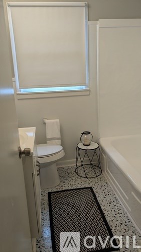 A bathroom with a toilet, a tub, and a window.