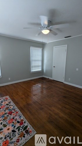 A room with a ceiling fan and a rug on the floor.