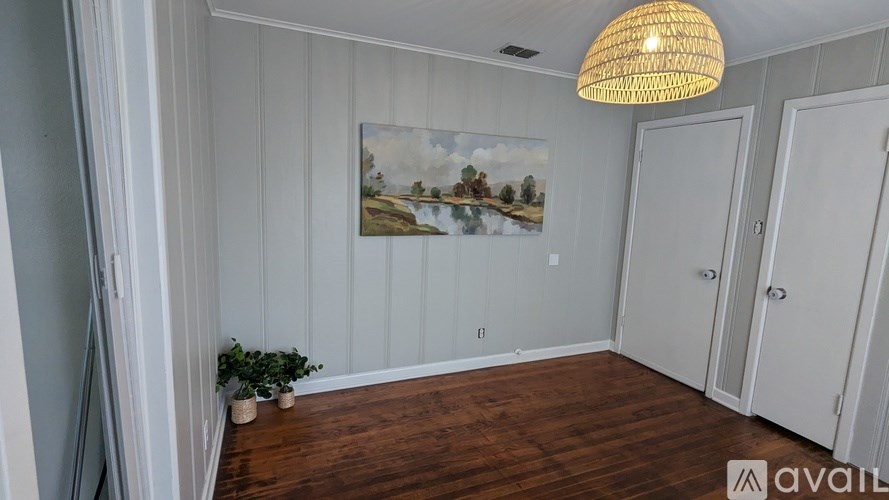 A room with a painting on the wall and a plant on the floor.