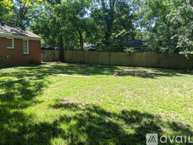 A backyard with a wooden fence and a house in the background.