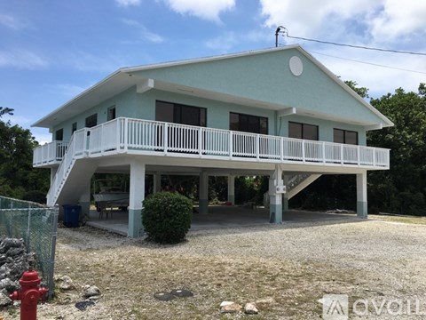 A two-story house with a balcony and a fire hydrant in front.