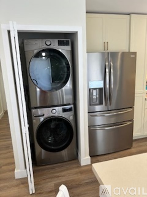 A modern kitchen with a stainless steel refrigerator and a washing machine.