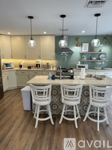 A kitchen with white chairs and a counter.