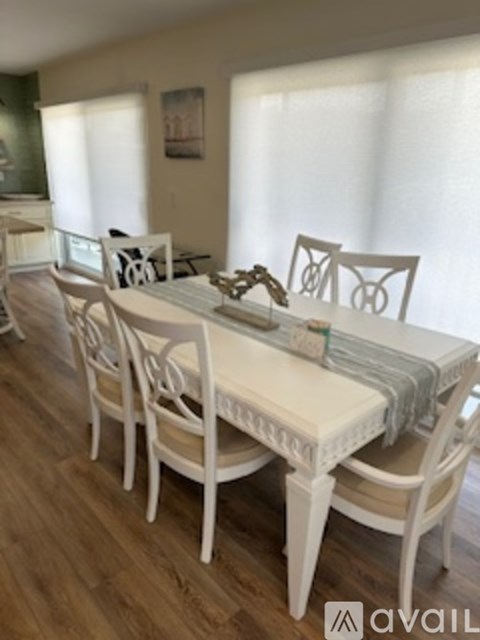 A white dining table with chairs and a tablecloth.