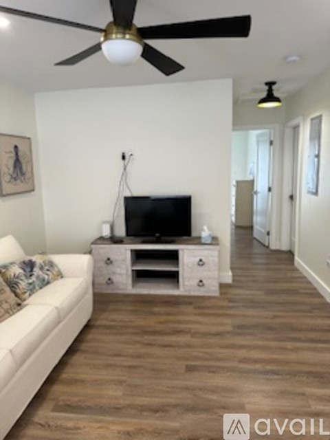 A living room with a white couch and a television on a cabinet.