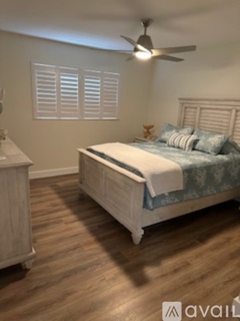 A bedroom with a bed, nightstand, and a ceiling fan.
