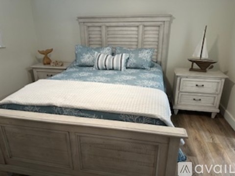 A bed with a white headboard and a blue comforter with a white pillow on it.