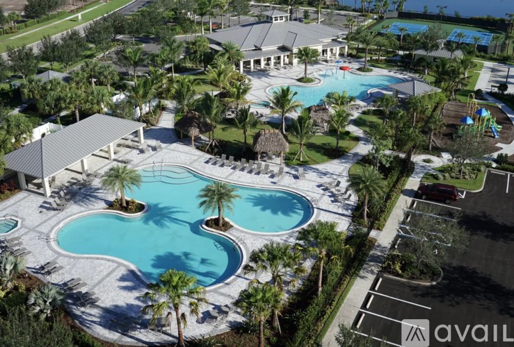 A large outdoor swimming pool surrounded by palm trees and a pavilion.