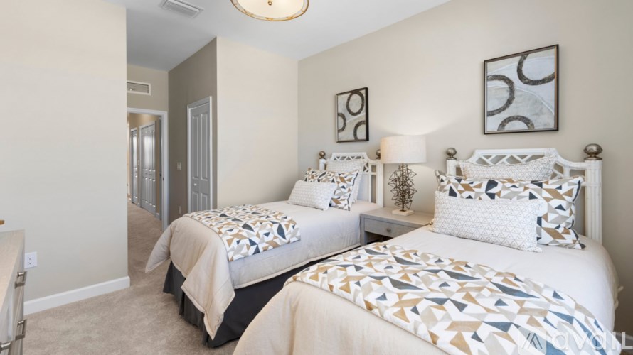 Two twin beds with patterned bedspreads in a room with two wall art pieces.