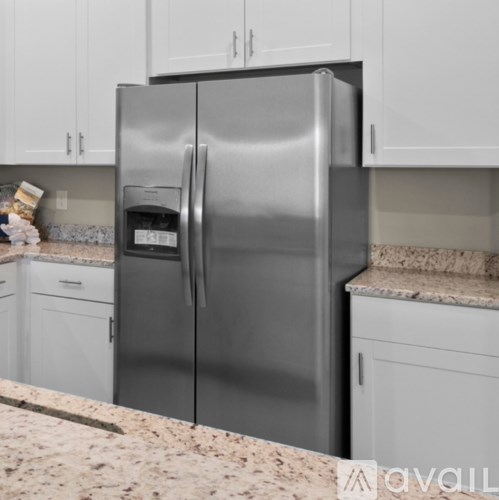 A stainless steel refrigerator in a kitchen with white cabinets.