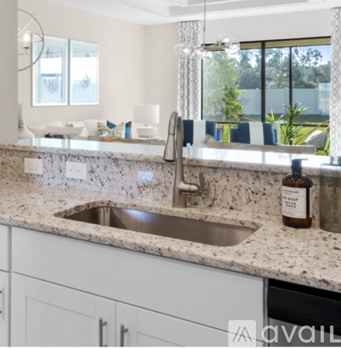 A kitchen with a marble countertop and a stainless steel sink.