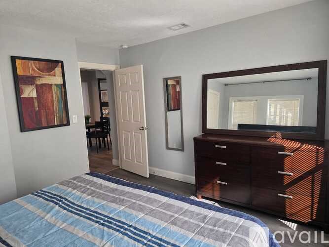 A bedroom with a bed, dresser, and mirror.