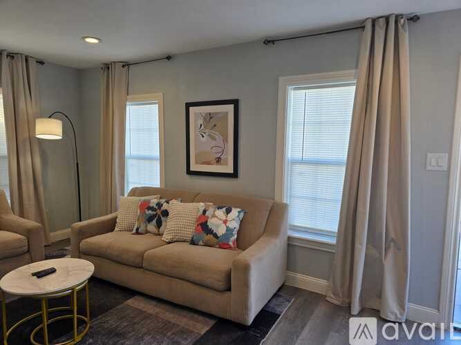 A living room with a beige couch, a round table, and a painting on the wall.