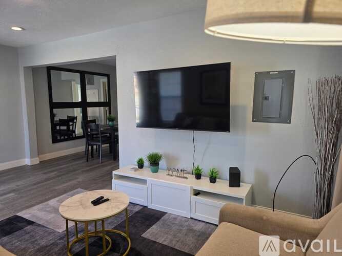A living room with a television, a table, and a plant.
