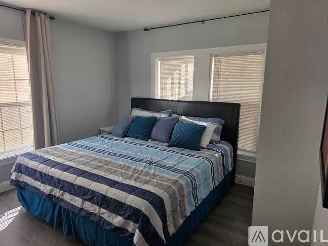 A bed with a blue and white striped comforter is in a room with a window.