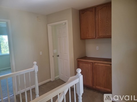 A room with a white door and wooden cabinets.