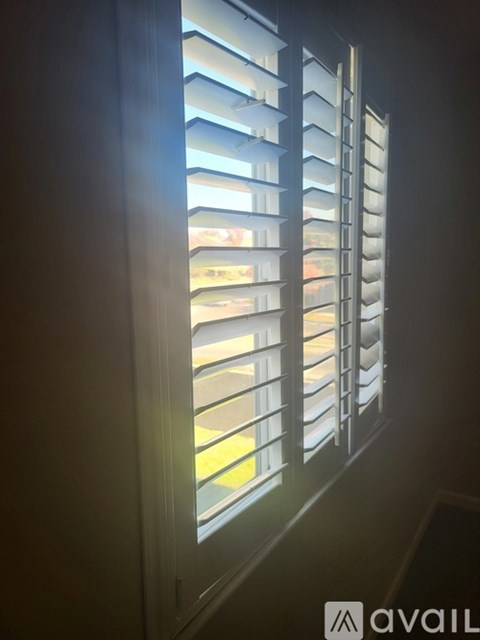 A window with white blinds is open, letting in light.