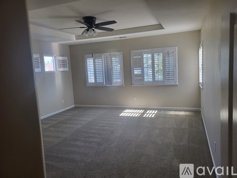 A room with a ceiling fan and carpeted floor.
