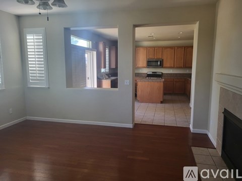 A room with wooden floors and a kitchen in the background.