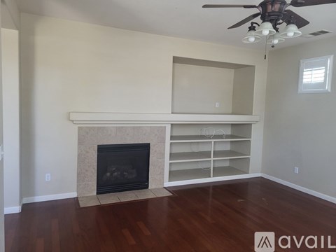 A living room with a fireplace and a ceiling fan.