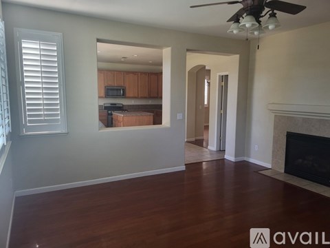 A spacious living room with a fireplace and a ceiling fan.