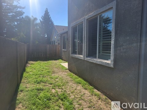 A backyard with a fence and a house in the background.