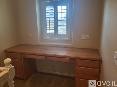 A wooden desk with a window above it in a room.