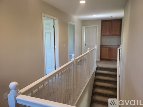 A staircase with a white railing leads to a kitchen area.