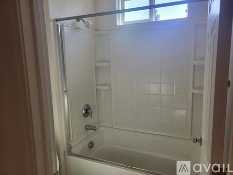 A white tiled shower stall with a glass door and a shower head.