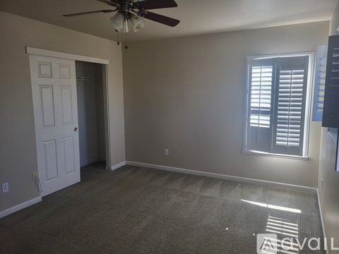 A room with a ceiling fan and a window with closed blinds.