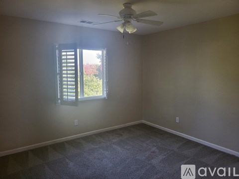 A room with a ceiling fan and a window with closed shutters.