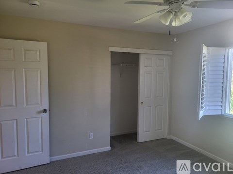 A room with a ceiling fan and two doors.
