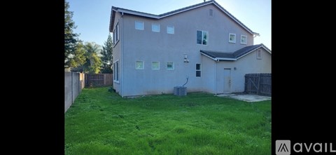 A house with a brown roof and a green lawn in front.