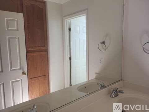 A bathroom with a sink, mirror, and a door.