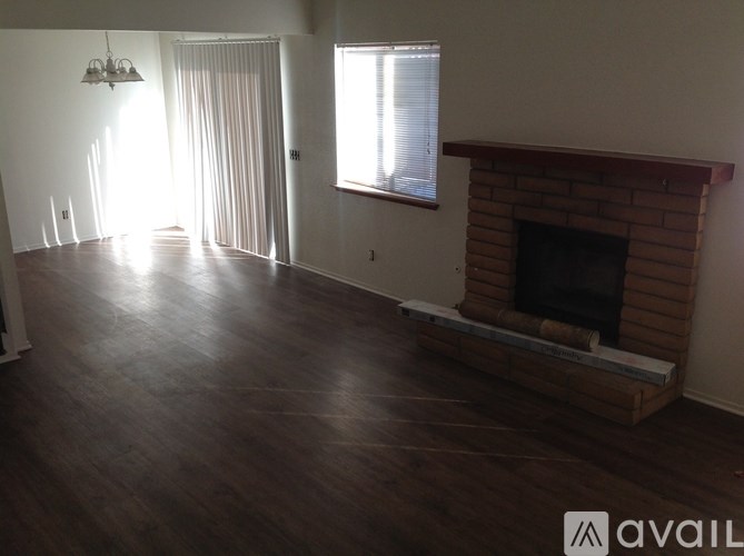A living room with a fireplace and a window with blinds.