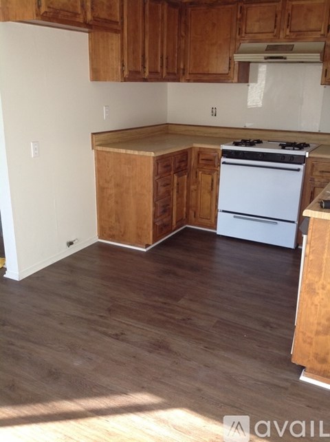 A kitchen with wooden cabinets and a white stove top oven.