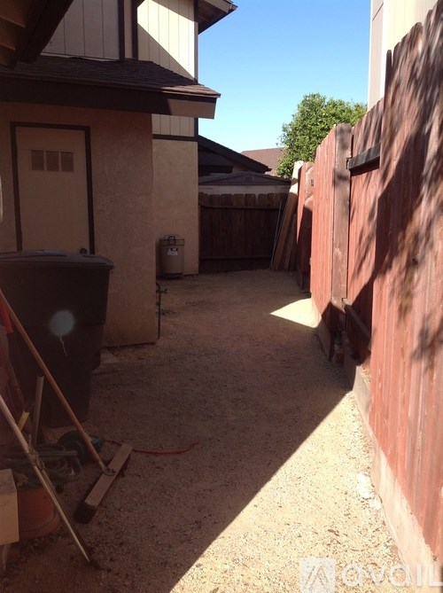 A backyard with a wooden fence and a trash can.