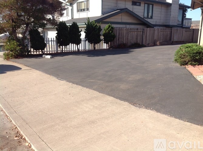 A driveway with a white fence and a house in the background.