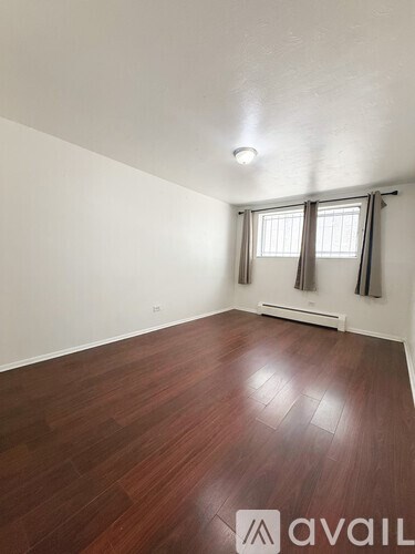 A room with wooden flooring and a window with curtains.
