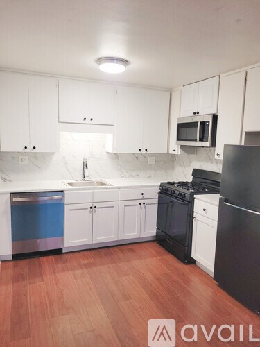 A kitchen with white cabinets and black appliances.