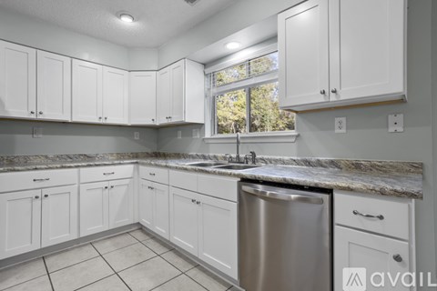 A kitchen with white cabinets and a marble countertop.