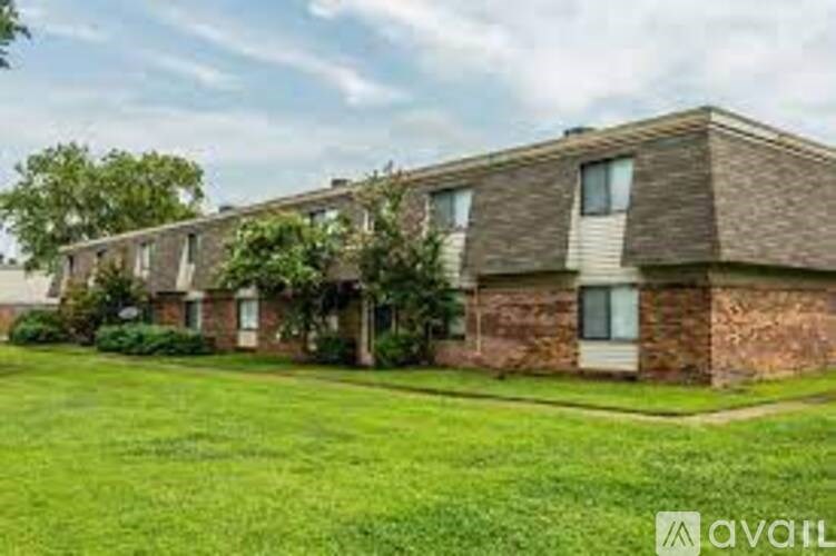 A brick apartment building with a green lawn in front.