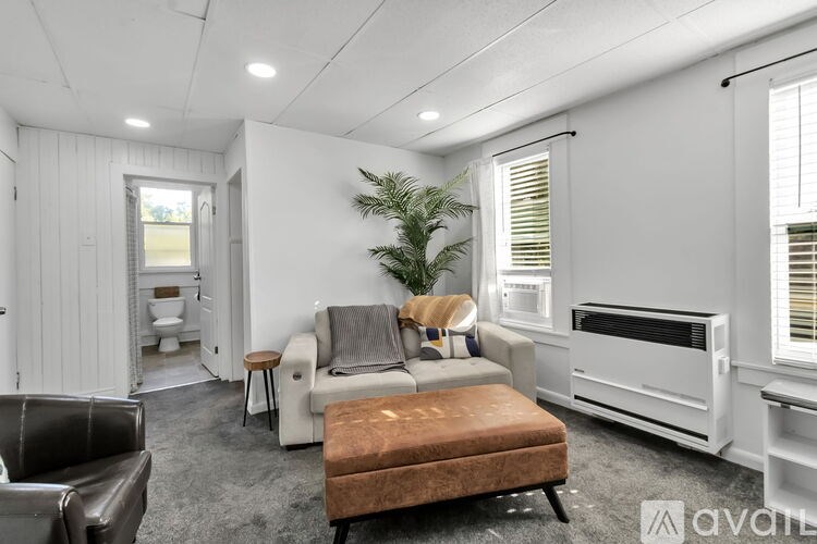A living room with a brown ottoman and a grey couch.